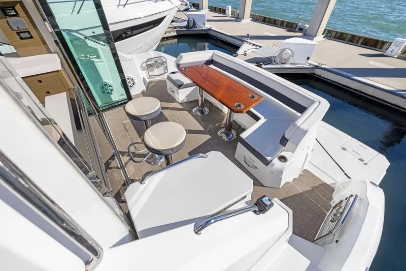 Slide: The Image of 2019 Cruisers Yachts 54 Cantius cockpit with seating and table, docked by the water. - 19