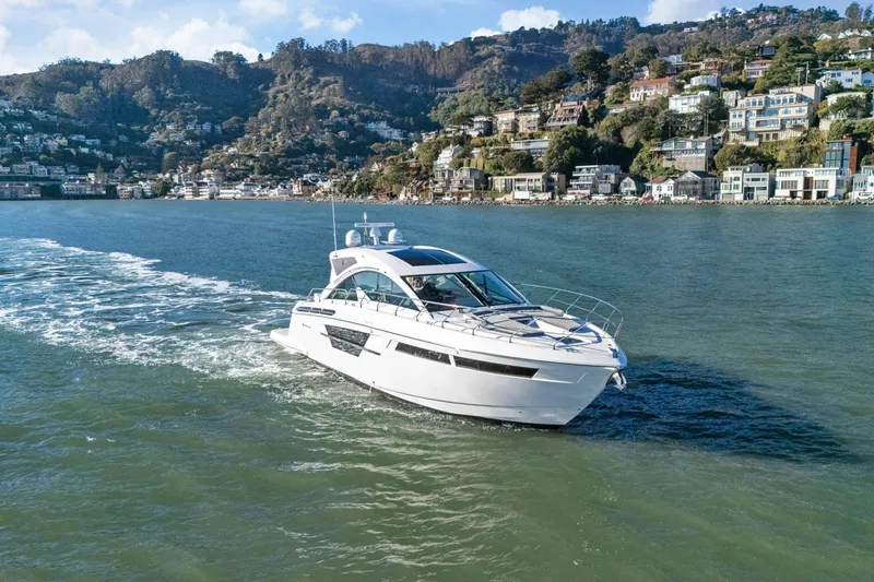 Slide: The Image of 2019 Cruisers Yachts 54 Cantius sailing near scenic coastal town. - 115