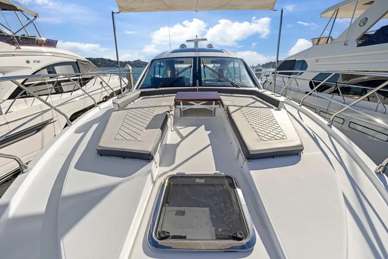 Slide: The Image of 2019 Cruisers Yachts 54 Cantius with sunbathing deck, docked among other luxury boats. - 15