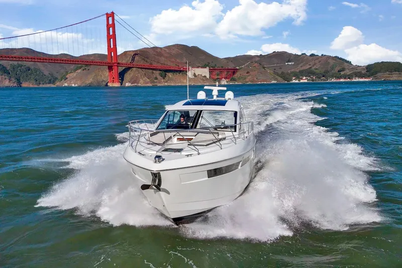 Slide: The Image of 2019 Cruisers Yachts 54 Cantius cruising near iconic red bridge on sunny day. - 2