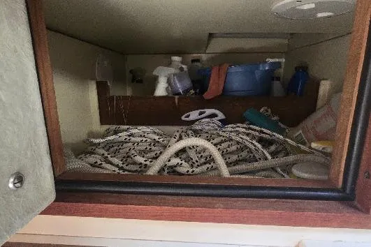 Slide: The Image of Storage compartment in a 1978 Tartan T34c sailboat with ropes and cleaning supplies. - 74