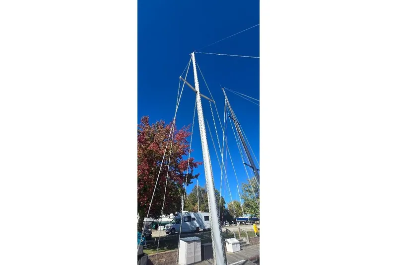 Slide: The Image of Mast of 1978 Tartan T34c sailboat against clear blue sky, surrounded by trees. - 17