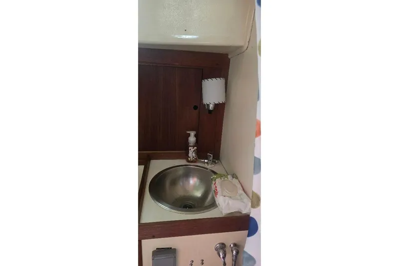 Slide: The Image of 1978 Tartan T34c yacht bathroom sink with wooden paneling and soap dispenser. - 23