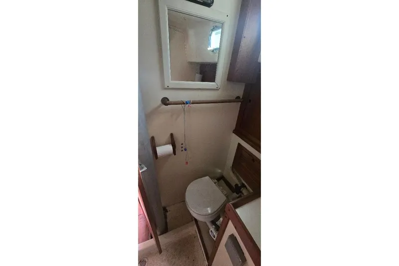 Slide: The Image of 1978 Tartan T34c yacht bathroom with toilet, mirror, and wooden cabinets. - 25
