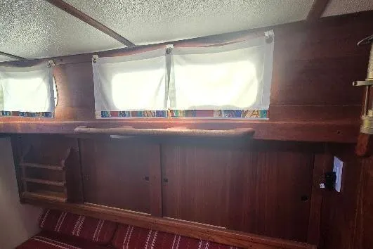 Slide: The Image of Interior of 1978 Tartan T34c sailboat with wooden cabinets and colorful curtains. - 47
