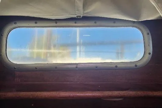 Slide: The Image of Porthole view from 1978 Tartan T34c sailboat, showcasing blue sky and clouds. - 53