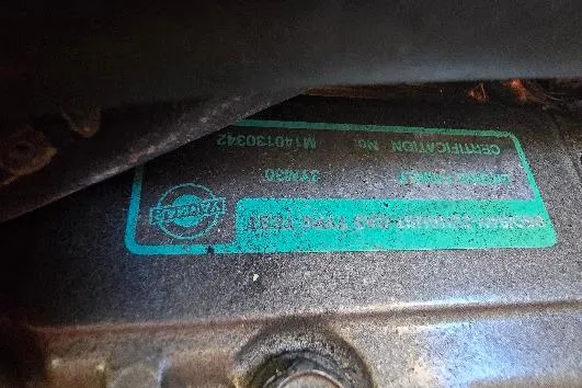 Slide: The Image of 1978 Tartan T34c engine plate with certification details and serial number. - 63