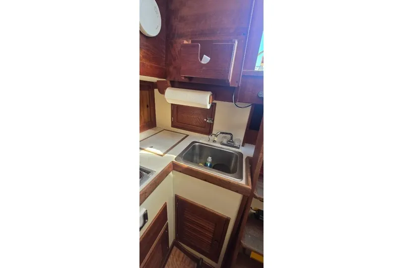 Slide: The Image of 1978 Tartan T34c yacht kitchen with sink, wooden cabinets, and paper towel holder. - 71