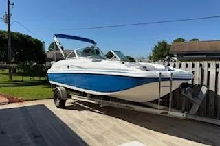 Slide: The Image of 2013 Hurricane SunDeck 187 OB boat on trailer, blue and white, parked outdoors. - 0