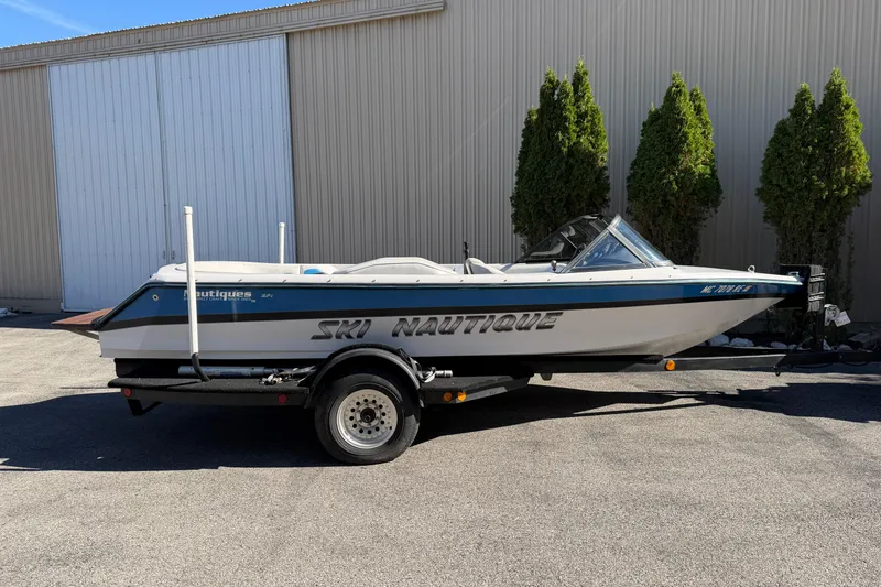 The Image of 1995 Correct Craft Ski Nautique boat on trailer, parked outdoors. - 0
