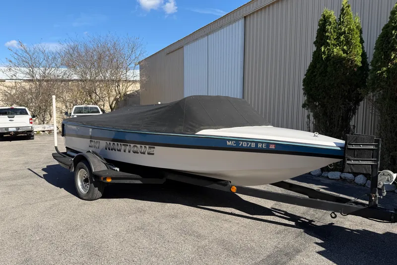 Slide: The Image of 1995 Correct Craft Ski Nautique boat on trailer, covered, parked outdoors. - 11