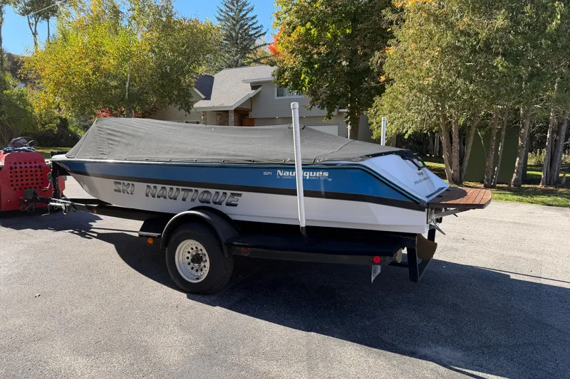 Slide: The Image of 1995 Correct Craft Ski Nautique boat on trailer, covered, parked outdoors. - 12