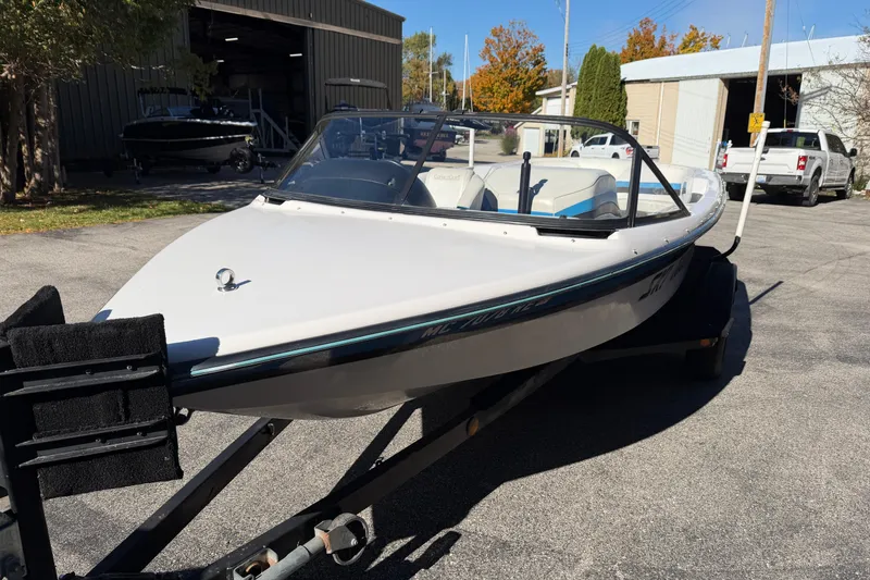 Slide: The Image of 1995 Correct Craft Ski Nautique boat on trailer, parked outdoors near buildings. - 2