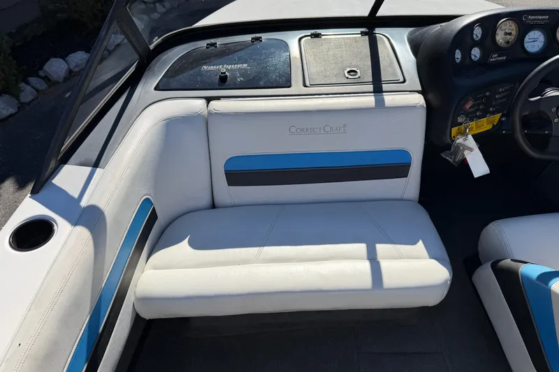 Slide: The Image of 1995 Correct Craft Ski Nautique interior with white and blue seating, dashboard, and steering wheel. - 24