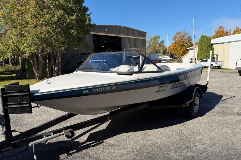 Slide: The Image of 1995 Correct Craft Ski Nautique boat on trailer, parked outdoors near buildings and trees. - 3