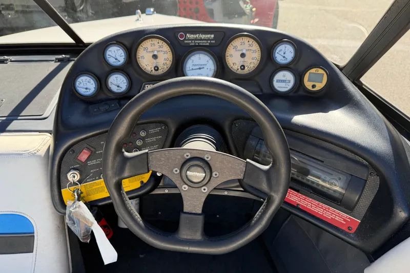 Slide: The Image of 1995 Correct Craft Ski Nautique dashboard with steering wheel and gauges. - 32
