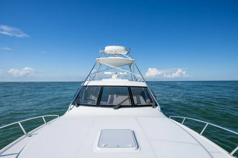 Slide: The Image of 2012 Cabo 40 Hardtop Express yacht cruising on open sea under clear blue sky. - 22
