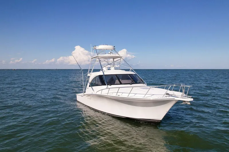 Slide: The Image of 2012 Cabo 40 Hardtop Express yacht cruising on open water under clear skies. - 48