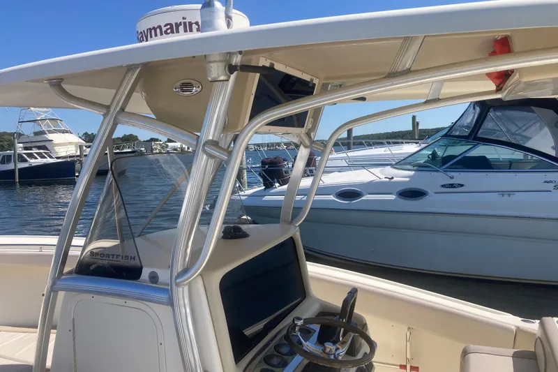 Slide: The Image of 2007 Scout 262 Sportfish boat docked, featuring steering console and nearby yachts. - 3