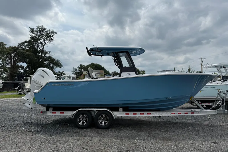 The Image of 2026 Sportsman Open 252 Center Console boat on trailer, cloudy sky background. - 0