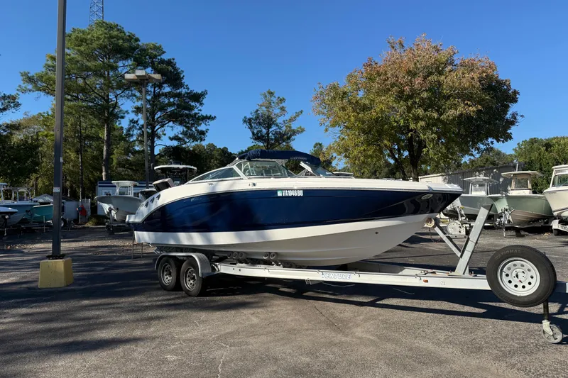 The Image of 2012 Chaparral 246 SSi boat on trailer in parking lot, surrounded by trees. - 0