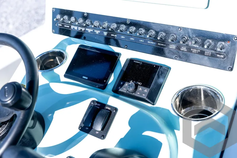 Slide: The Image of 2026 Pathfinder 2200 TRS boat dashboard with controls, switches, and cup holders. - 57