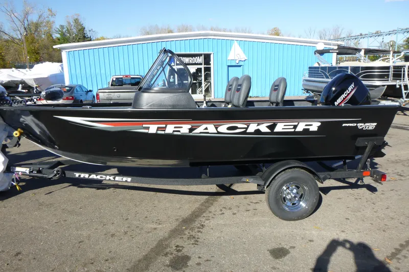 The Image of 2026 Tracker Pro Guide V-16 WT boat on trailer outside blue building. - 1
