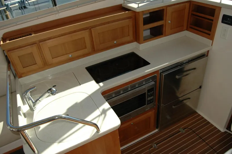 Slide: The Image of 2015 Back Cove 37 yacht kitchen with sink, stove, microwave, and wooden cabinetry. - 41