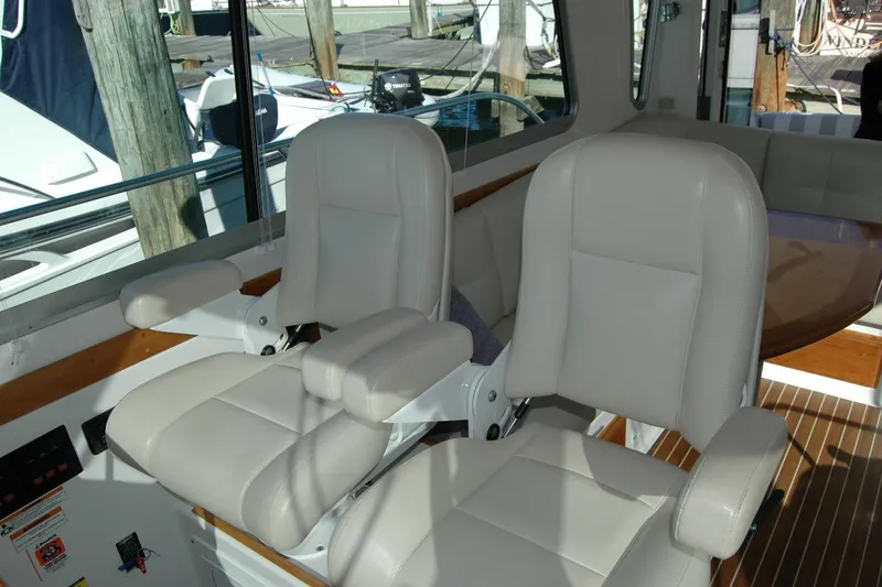 Slide: The Image of 2015 Back Cove 37 interior with two white captain chairs and wooden accents. - 48