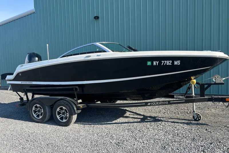 The Image of 2022 Four Winns HD2 OB boat on trailer, parked outdoors near a blue building. - 0