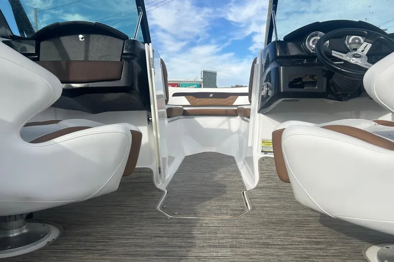 Slide: The Image of 2022 Four Winns HD2 OB boat interior with white and brown seating, steering wheel, and dashboard. - 19