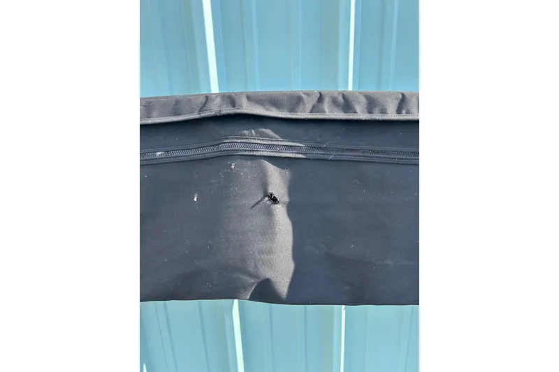Slide: The Image of Black fabric with a small tear, possibly a boat cover, against a blue background. - 50