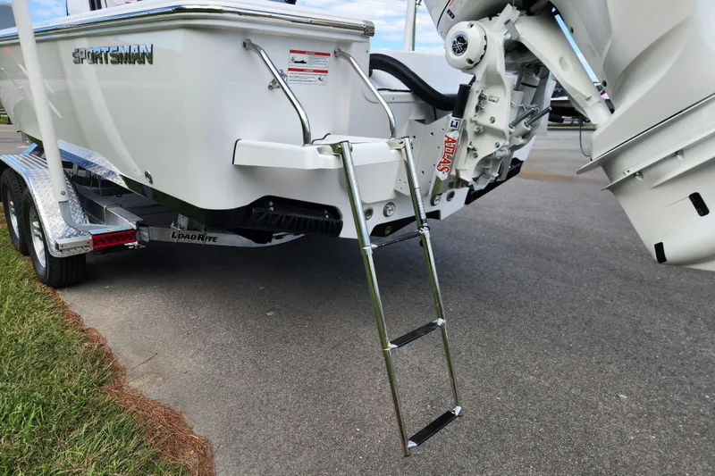 Slide: The Image of 2026 Sportsman Masters 247 Bay Boat with ladder and trailer on pavement. - 8