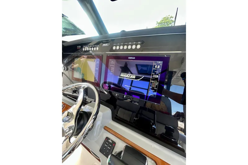 Slide: The Image of 2023 Boston Whaler 360 Outrage dashboard with Simrad display and steering wheel. - 12