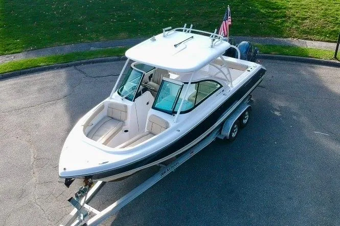 Slide: The Image of 2018 Pursuit DC 265 Dual Console boat on trailer, parked outdoors. - 0