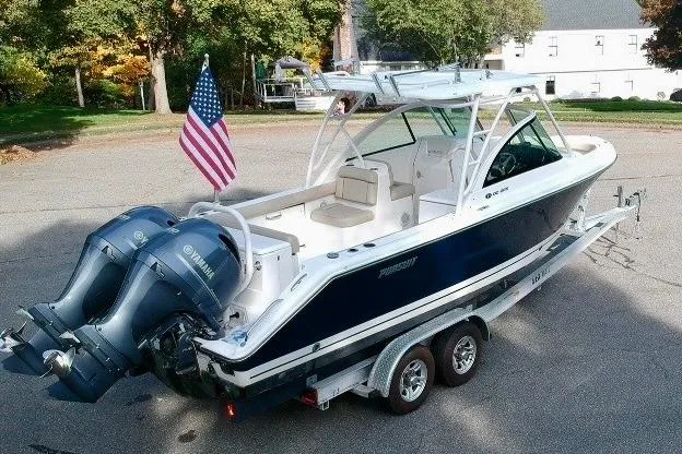 Slide: The Image of 2018 Pursuit DC 265 Dual Console boat on trailer with twin Yamaha engines and American flag. - 1