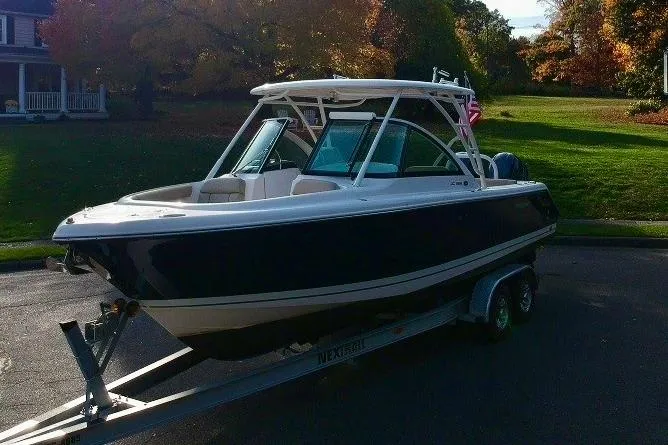Slide: The Image of 2018 Pursuit DC 265 Dual Console boat on trailer, parked outdoors. - 2