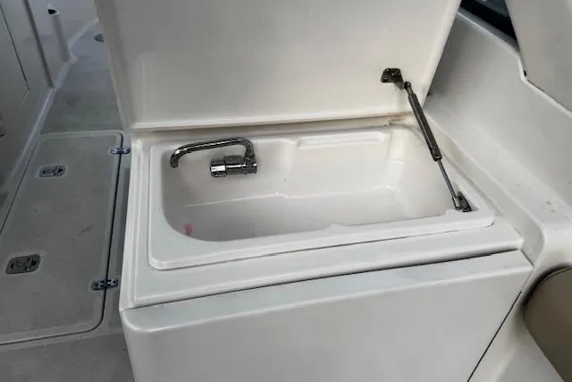 Slide: The Image of 2018 Pursuit DC 265 Dual Console boat sink with faucet, white interior. - 24