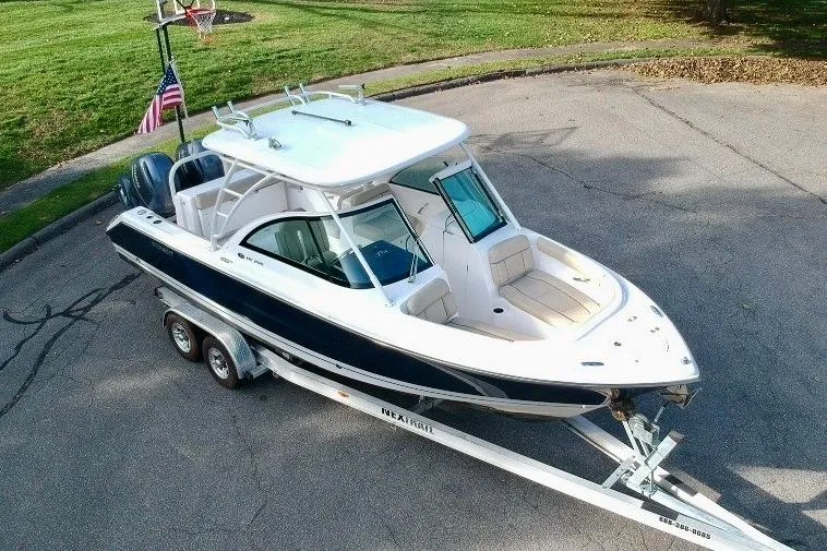Slide: The Image of 2018 Pursuit DC 265 Dual Console boat on trailer, parked outdoors. - 5