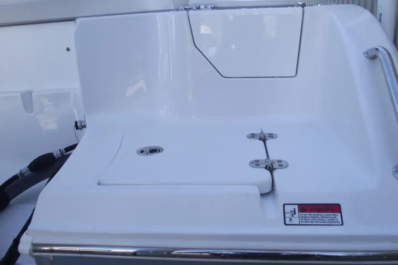 Slide: The Image of 2023 Sea Hunt Ultra 255 SE boat deck with storage compartment and safety warning label. - 40