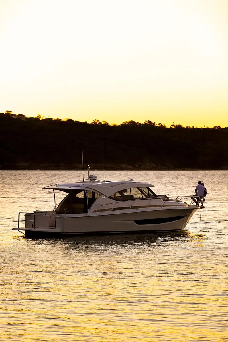 Slide: The Image of 2024 Riviera 395 SUV boat at sunset on calm water. - 5