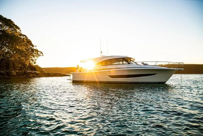 Slide: The Image of 2024 Riviera 395 SUV yacht on serene water at sunset. - 6