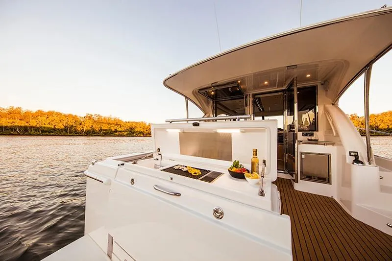 Slide: The Image of 2024 Riviera 395 SUV yacht with outdoor kitchen on a serene river. - 8