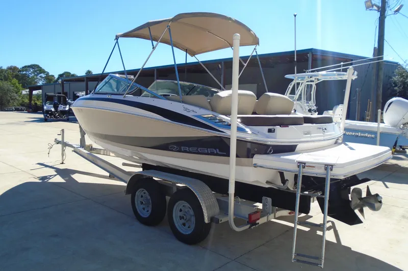 Slide: The Image of 2014 Regal 2300 Bowrider boat on trailer with canopy, parked outdoors. - 4