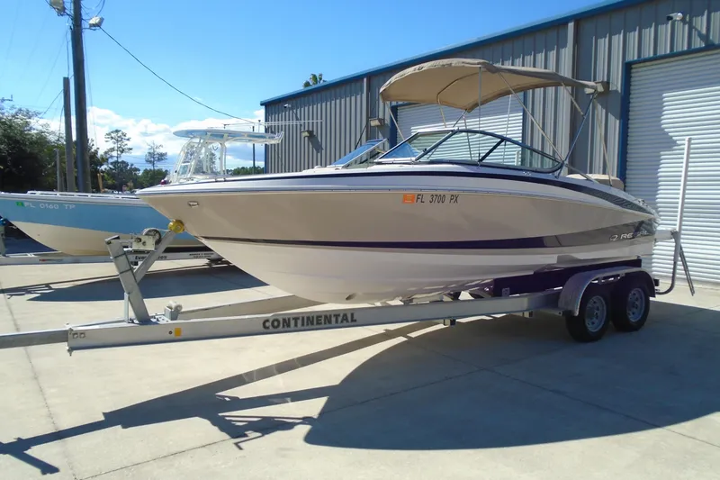 Slide: The Image of 2014 Regal 2300 Bowrider boat on trailer, parked outdoors near a building. - 5