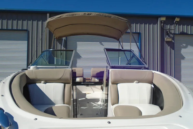 Slide: The Image of 2014 Regal 2300 Bowrider boat with beige seating and canopy, docked near a building. - 6