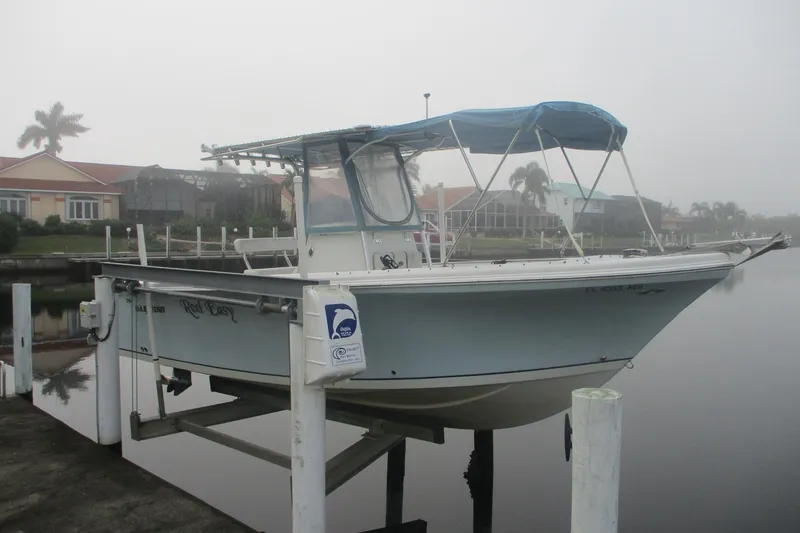 The Image of 2005 Sailfish 236 CC boat on lift, docked near waterfront homes. - 0