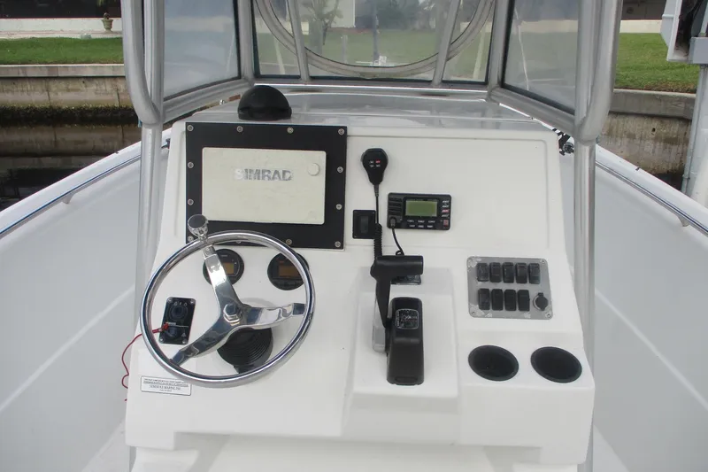 Slide: The Image of 2005 Sailfish 236 CC boat console with steering wheel, controls, and Simrad display. - 12