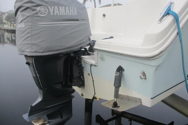 Slide: The Image of 2005 Sailfish 236 CC boat with Yamaha outboard motor, docked by calm water. - 2