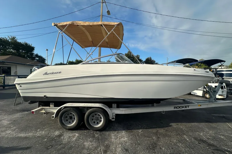 Slide: The Image of 2020 Hurricane SunDeck 217 OB boat on trailer with canopy, parked outdoors. - 1